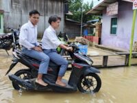 Warga Desa Batu Timbau Ulu nekat melintasi genangan banjir akibat luapan Sungai Merban. (Dok: Polres Kutim)