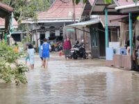 Warga melintasi genangan banjir yang merendam permukiman di Kecamatan Sangatta, Kutim, akibat hujan deras dan kiriman air dari wilayah hulu.(Dok: tio/expresi)